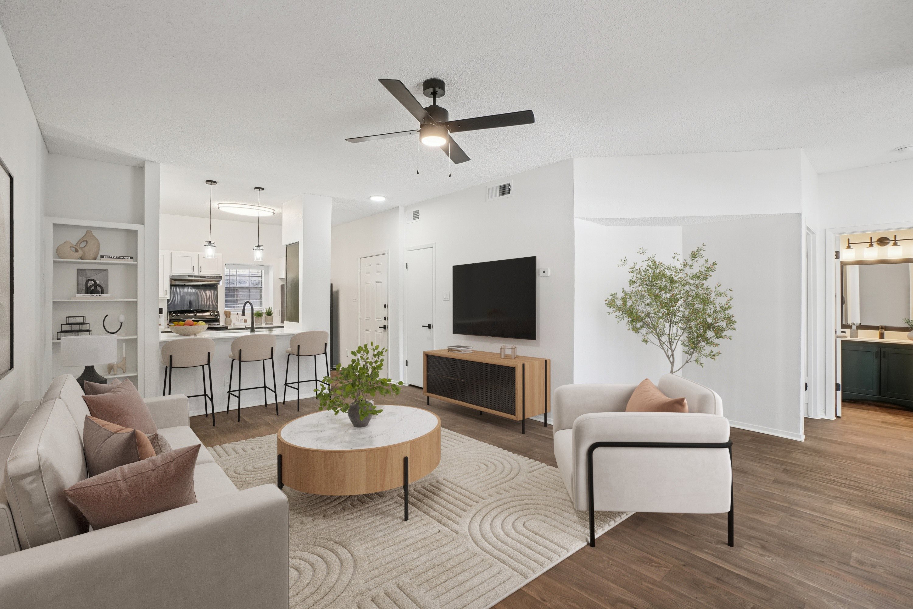 A living room with a white couch, a wooden coffee table, and a ceiling fan.